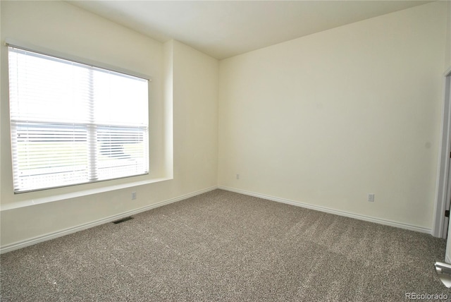 spare room featuring baseboards, visible vents, and carpet flooring