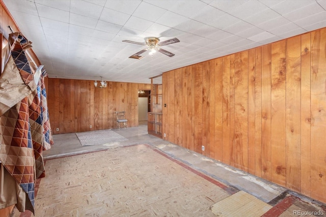 unfurnished room featuring ceiling fan and wooden walls