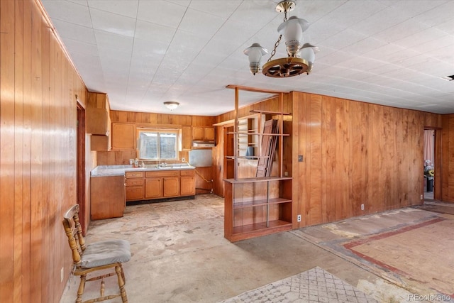 kitchen featuring wood walls, sink, and a chandelier