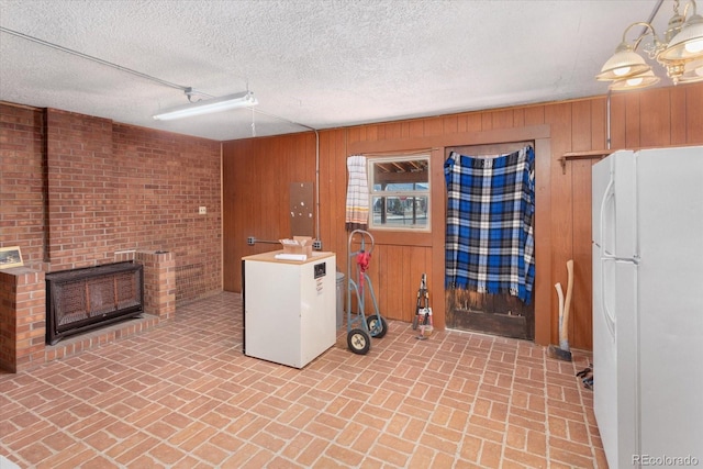 interior space with wood walls, a textured ceiling, and brick wall