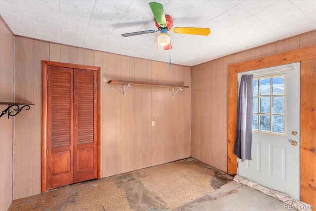 interior space featuring ceiling fan and wood walls