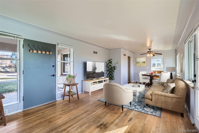 living room featuring ceiling fan, light wood finished floors, and visible vents