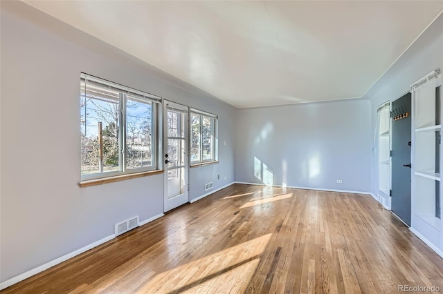 unfurnished room featuring hardwood / wood-style floors, visible vents, and baseboards