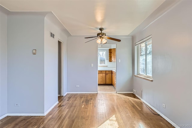 unfurnished room with baseboards, a wealth of natural light, visible vents, and light wood-style floors