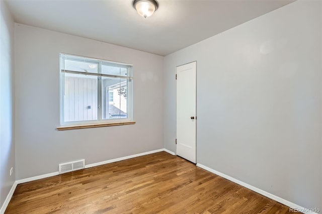 empty room with baseboards, visible vents, and wood finished floors