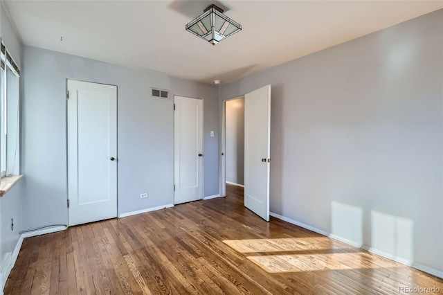 unfurnished bedroom with baseboards, visible vents, and hardwood / wood-style floors