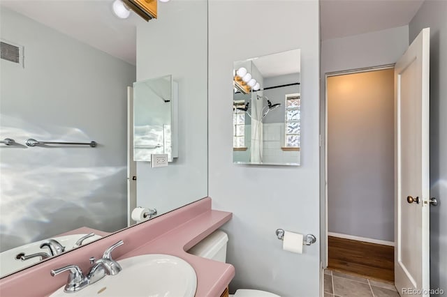 bathroom featuring visible vents, baseboards, toilet, tile patterned flooring, and vanity