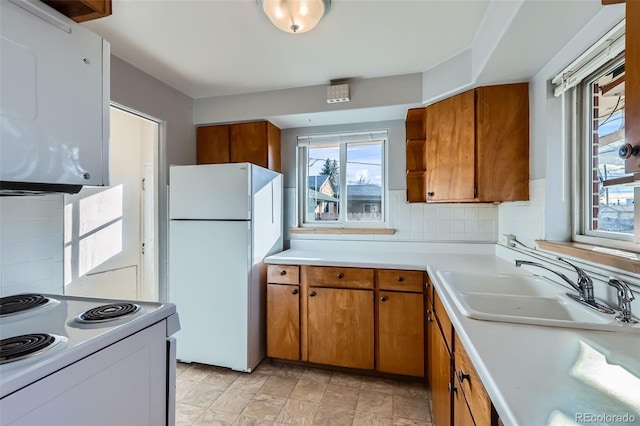 kitchen with white appliances, brown cabinetry, and light countertops