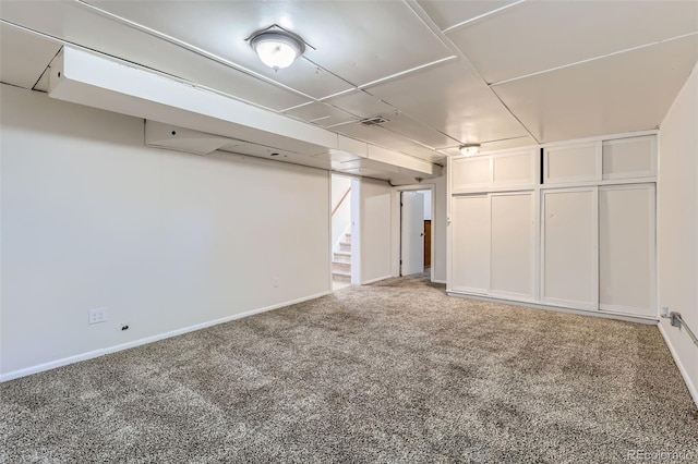 finished below grade area featuring carpet floors, visible vents, baseboards, and stairs