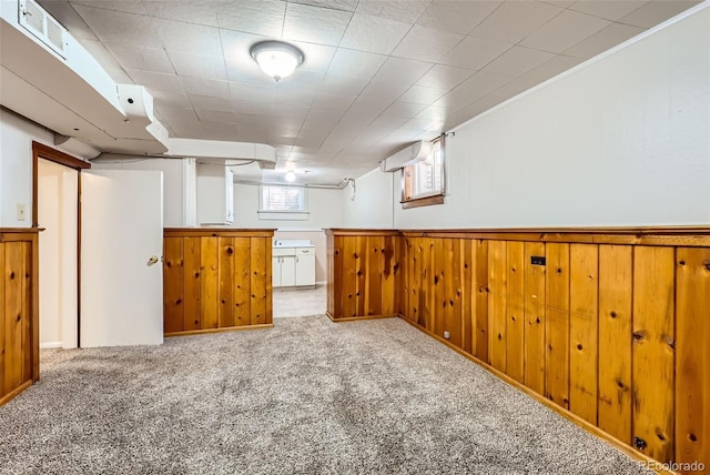 below grade area with carpet floors, wood walls, wainscoting, and visible vents