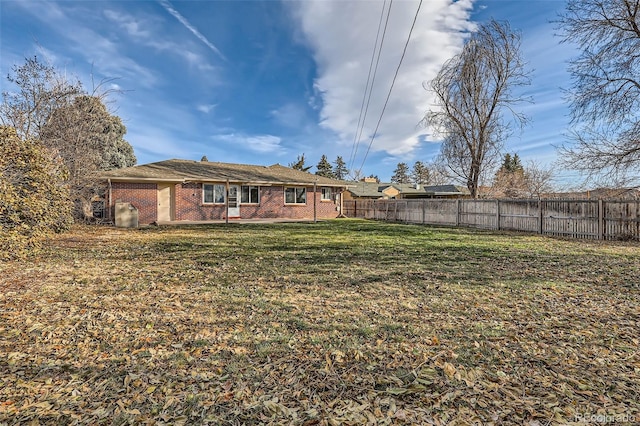 back of property with brick siding, a lawn, and fence