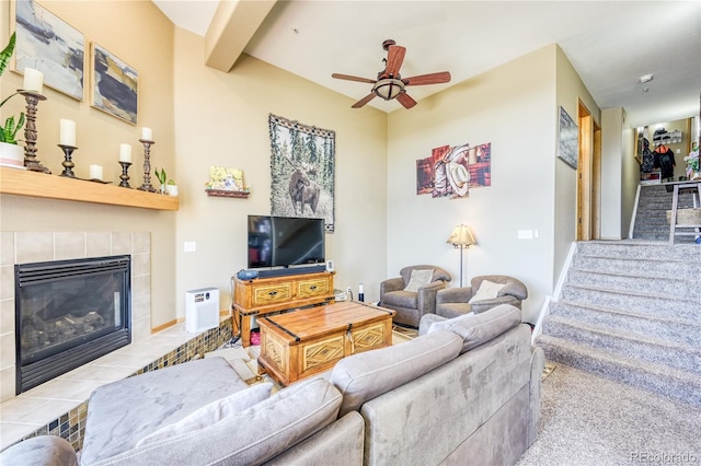 living room with a ceiling fan, a tile fireplace, and carpet