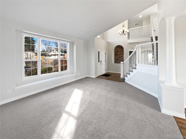 entryway featuring decorative columns, high vaulted ceiling, dark carpet, and an inviting chandelier