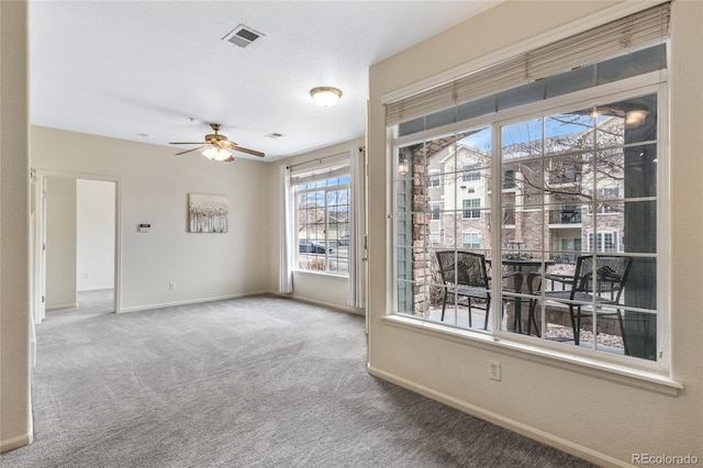 unfurnished room with a textured ceiling, ceiling fan, and carpet flooring