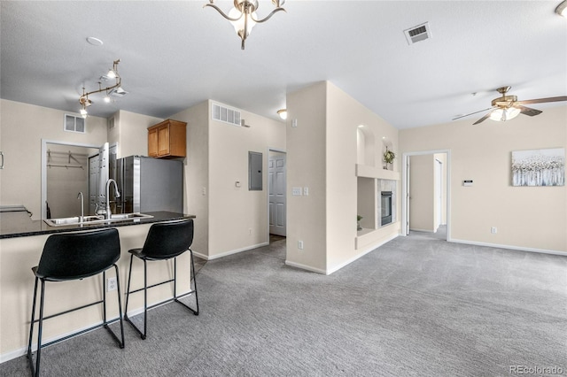 kitchen featuring a tile fireplace, sink, stainless steel fridge, electric panel, and light carpet