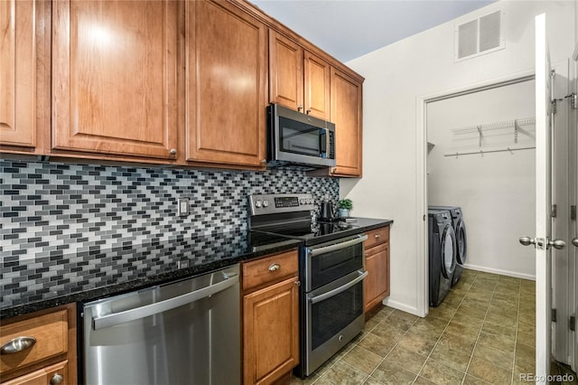 kitchen featuring stainless steel appliances, tasteful backsplash, dark stone countertops, and washing machine and clothes dryer