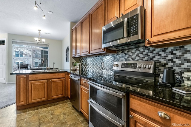 kitchen featuring tasteful backsplash, appliances with stainless steel finishes, kitchen peninsula, and sink