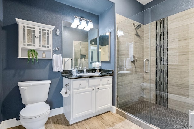 bathroom with vanity, wood-type flooring, a shower with door, and toilet