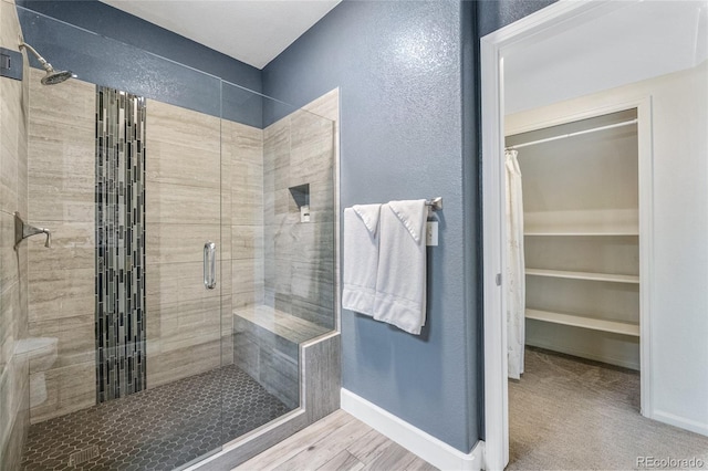 bathroom with a shower with shower door and wood-type flooring