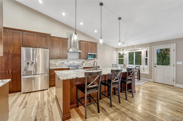 5402 S Queen Way, Littleton, CO 80127 - kitchen with appliances with stainless steel finishes, wall chimney range hood, light wood-style floors, a center island with sink, and decorative backsplash