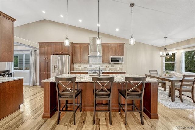 5402 S Queen Way, Littleton, CO 80127 - kitchen with appliances with stainless steel finishes, wall chimney range hood, vaulted ceiling, a spacious island, and backsplash