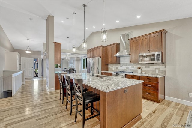 5402 S Queen Way, Littleton, CO 80127 - kitchen with stainless steel appliances, wall chimney exhaust hood, brown cabinets, decorative backsplash, and light wood-style flooring