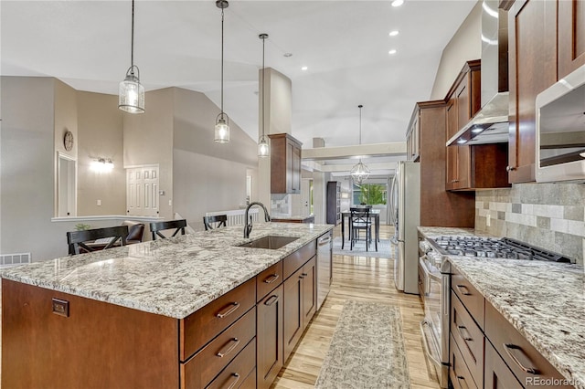 5402 S Queen Way, Littleton, CO 80127 - kitchen featuring stainless steel appliances, wall chimney range hood, light wood finished floors, tasteful backsplash, and light stone counters