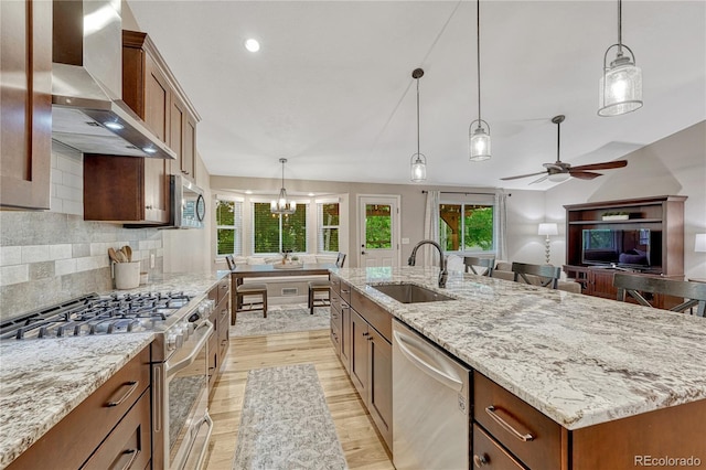 5402 S Queen Way, Littleton, CO 80127 - kitchen featuring appliances with stainless steel finishes, wall chimney exhaust hood, light wood-style flooring, a spacious island, and a ceiling fan