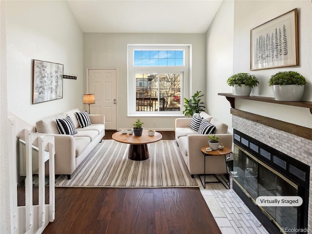 living room featuring wood-type flooring and a tiled fireplace