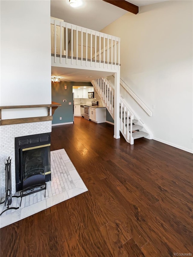 unfurnished living room with dark hardwood / wood-style flooring, vaulted ceiling with beams, and a tile fireplace