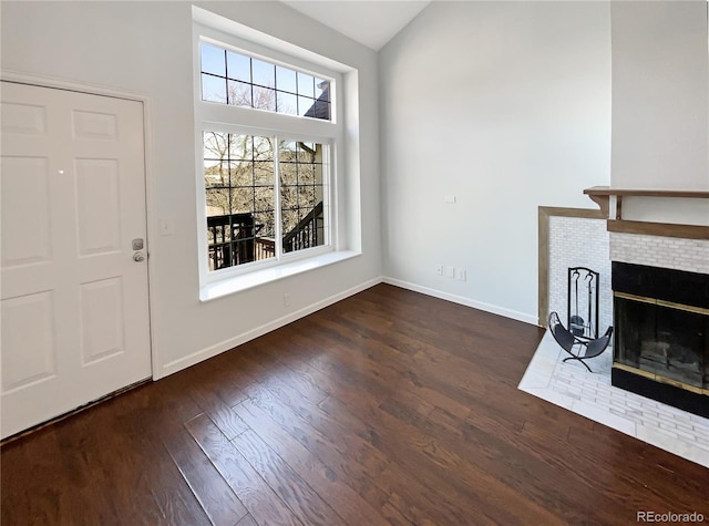 entrance foyer featuring dark hardwood / wood-style flooring, a fireplace, and vaulted ceiling