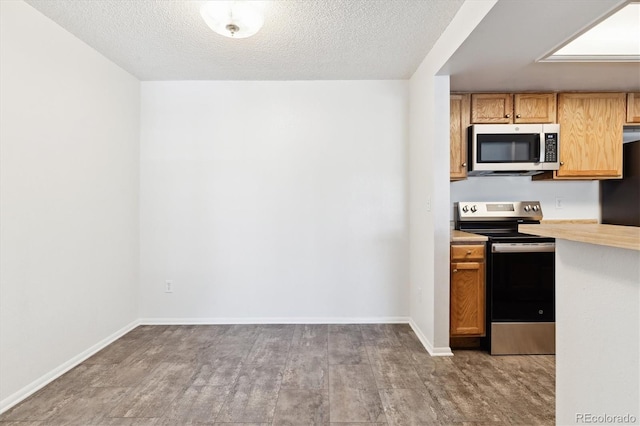 kitchen with light hardwood / wood-style floors, a textured ceiling, and appliances with stainless steel finishes