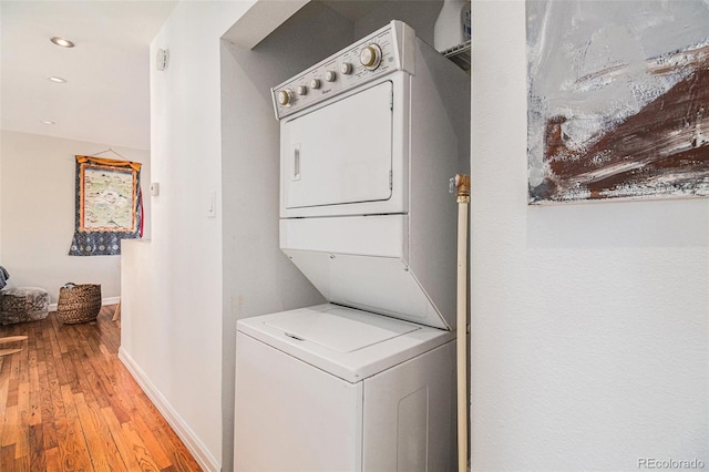 laundry room with light wood-type flooring and stacked washer and dryer