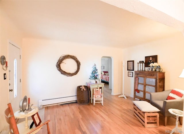 living area featuring wood-type flooring and a baseboard heating unit