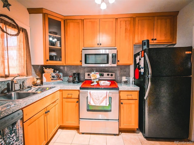 kitchen featuring light tile patterned floors, sink, backsplash, and black appliances