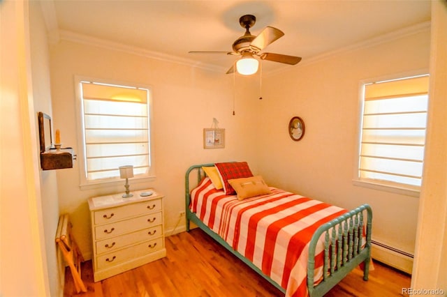 bedroom with hardwood / wood-style flooring, baseboard heating, crown molding, and ceiling fan