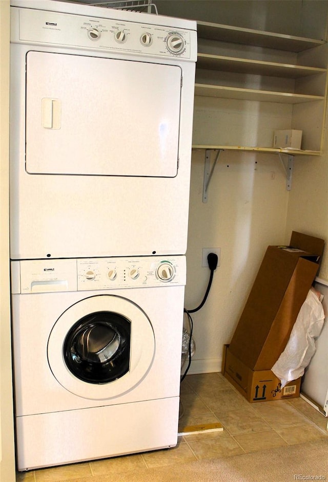 laundry area with stacked washer / dryer and light tile patterned floors