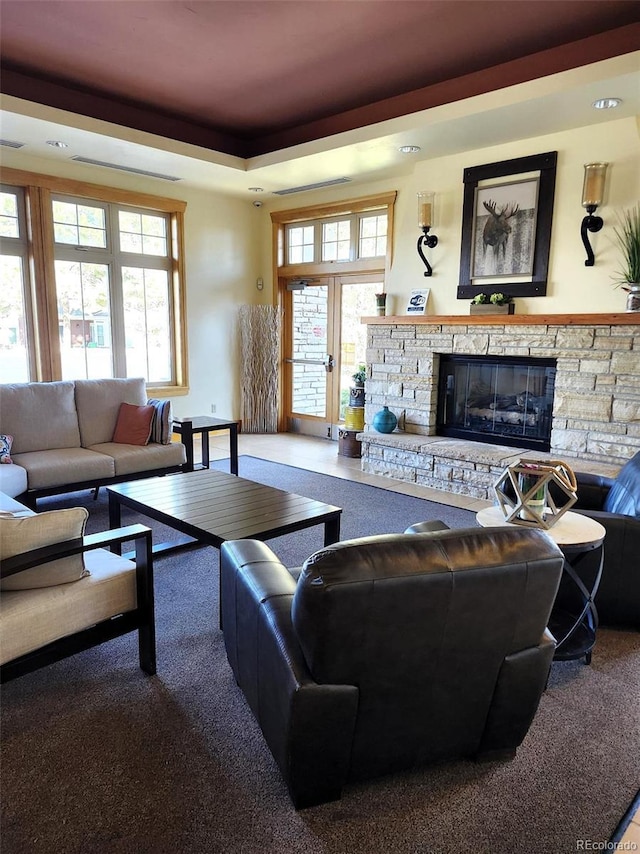 carpeted living room with a fireplace and a raised ceiling