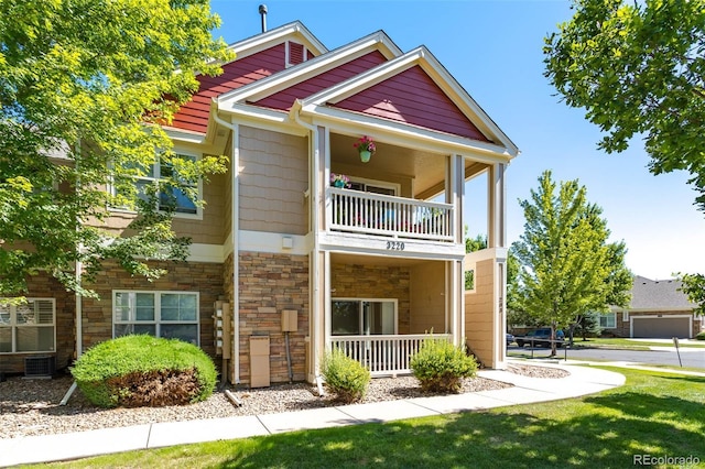 3220 Boulder Cir Unit 103, Broomfield, CO 80023 - view of front facade with a balcony, stone siding, a front lawn, and covered porch