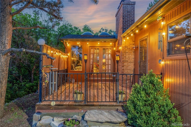 19 Rock Ln, Castle Rock, CO 80104 - exterior entry at dusk with a chimney, french doors, a gate, and brick siding