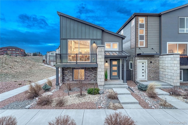 modern home featuring a standing seam roof, stone siding, board and batten siding, and metal roof