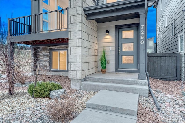 property entrance with stone siding and fence