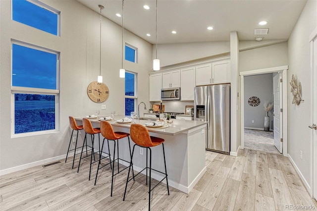 kitchen with visible vents, white cabinets, appliances with stainless steel finishes, a breakfast bar, and a peninsula