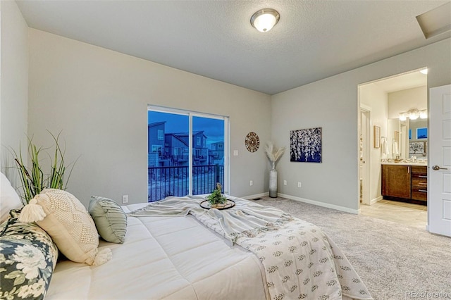 bedroom featuring baseboards, light colored carpet, ensuite bath, access to exterior, and a textured ceiling