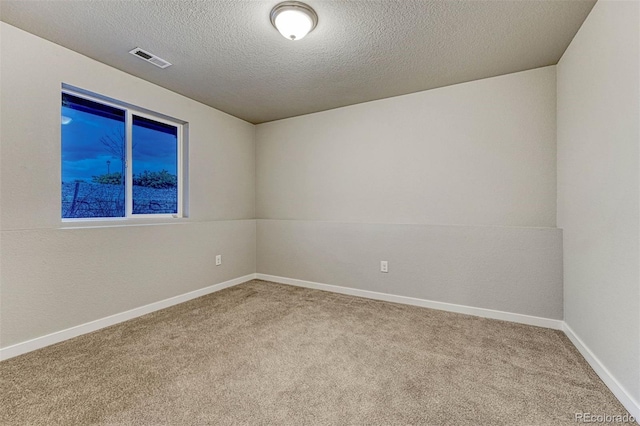 empty room featuring carpet flooring, visible vents, baseboards, and a textured ceiling