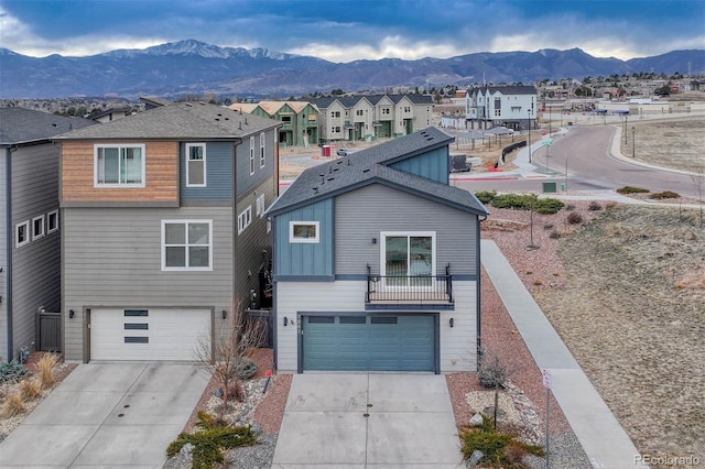 view of front of home with a mountain view, driveway, a residential view, and a garage