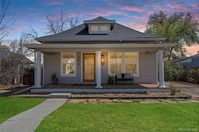 bungalow-style home with fence, covered porch, and a front yard
