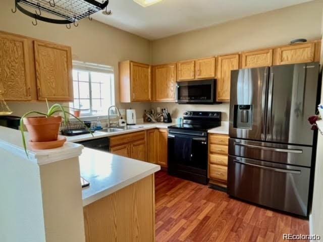 kitchen with wood finished floors, stainless steel appliances, light countertops, and a sink