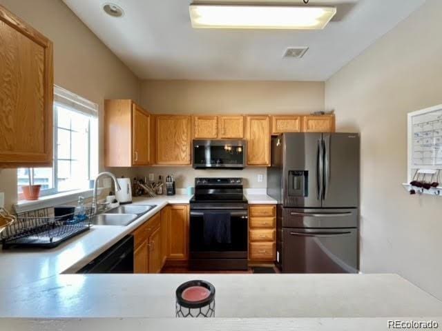 kitchen featuring black appliances, light countertops, visible vents, and a sink