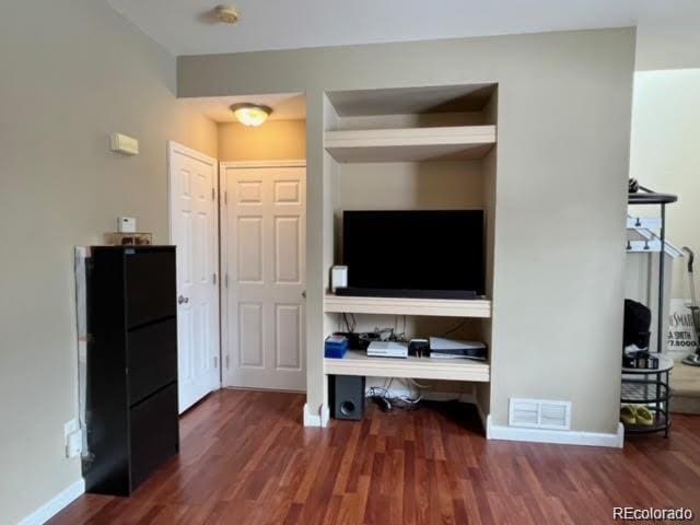 living area featuring wood finished floors, visible vents, and baseboards